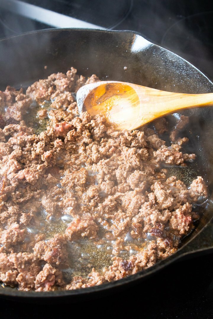 Ground beef sautéing in a cast iron skillet.