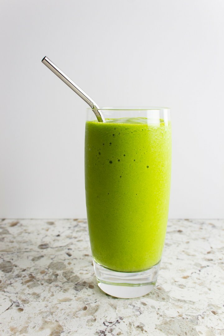 Mango Ginger Green Smoothie in a tall glass with a stainless steel straw.