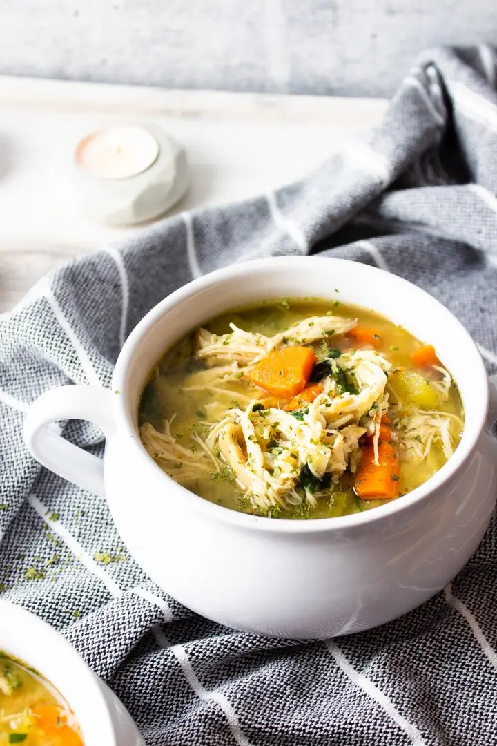 A close-up of Hearty AIP Chicken Vegetable Soup on a grey towel.