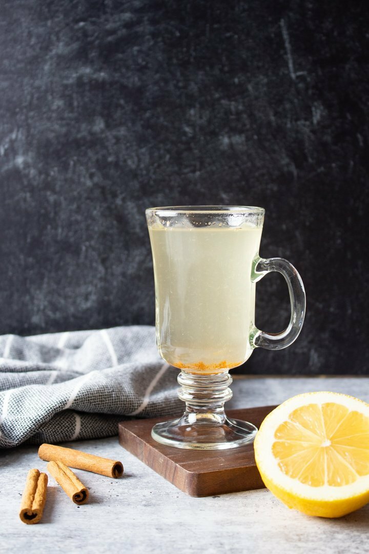 Virgin Hot Toddy in a glass mug with lemon and cinnamon sticks.